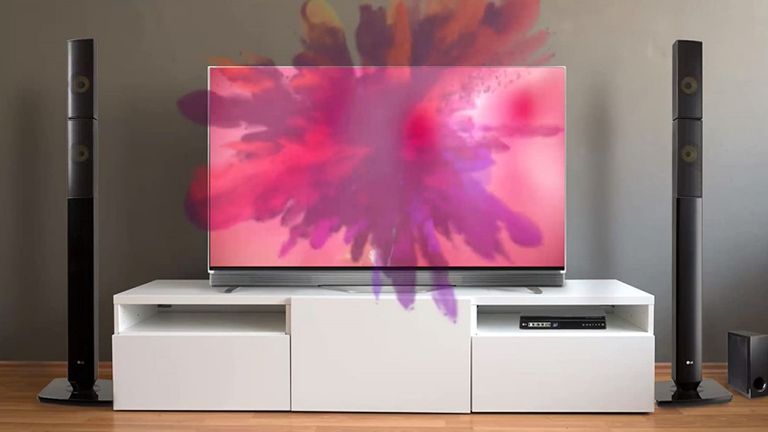 the LG LOUDR LHB645N Home Theatre Speaker System, one of the best surround sound system options, in a living room with a TV on top of a white stand