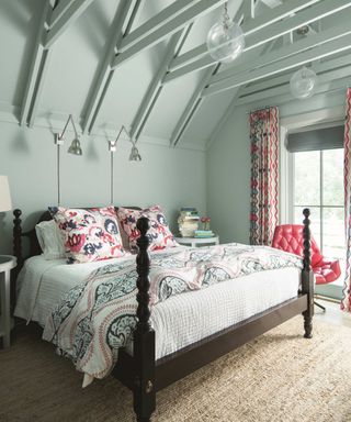 A four poster bed with paisley bedding in front of a light blue wall