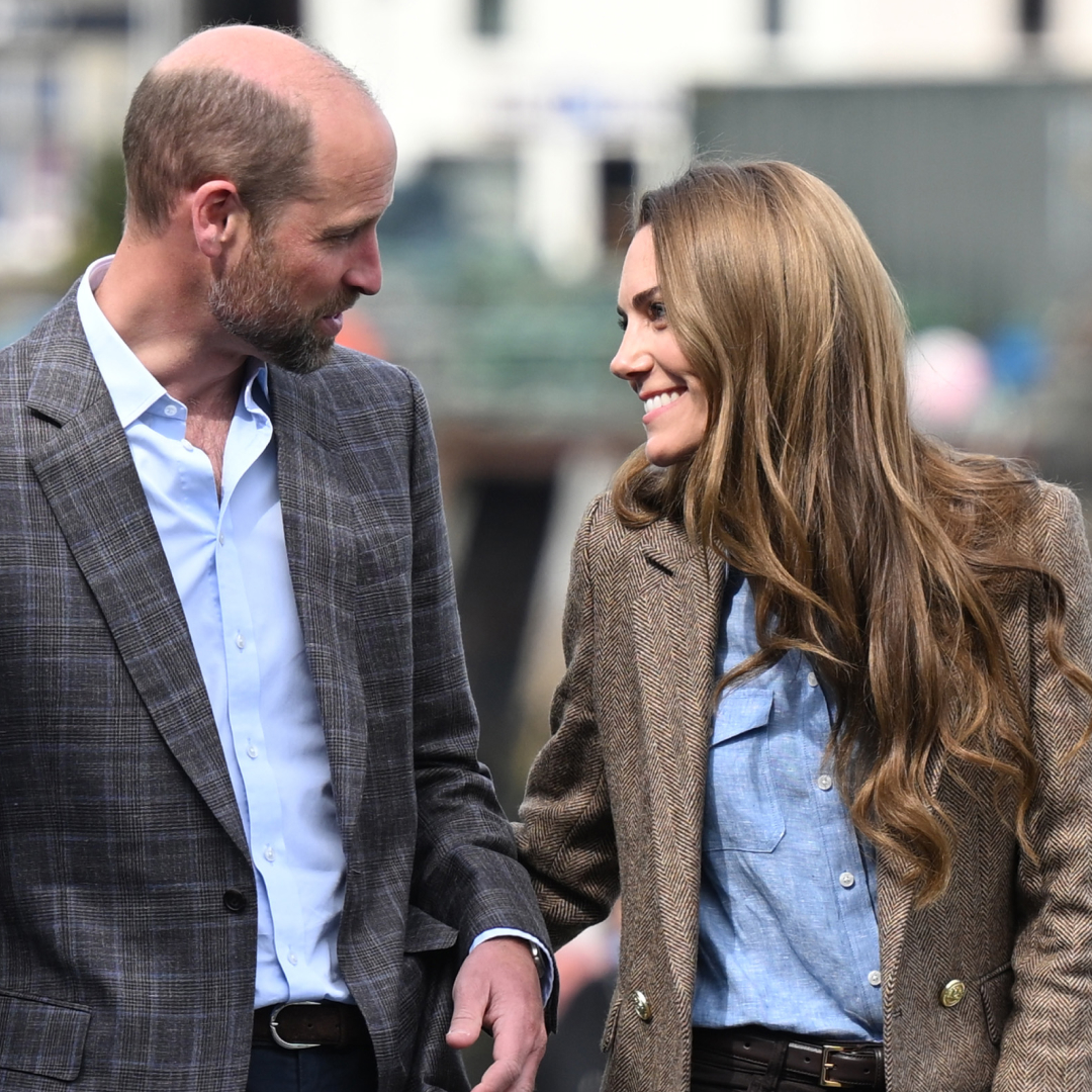 Kate Middleton and Prince William wearing blazers and smiling at each other