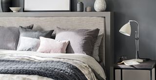 Charcoal gray bedroom with bed made properly with plenty of cushions and a gray throw to show how making a bed is an import daily habit to keep your house clean and tidy