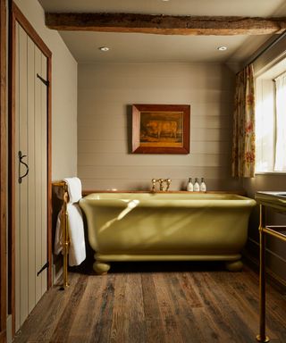 A rustic wood bathroom with neutral panelled walls and an avocado bathtub