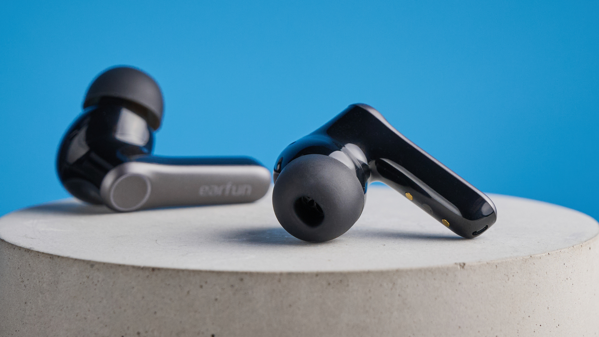 the earfun air pro 4+ earbuds in black showing the ear tips, charging case, and being worn