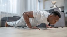Young African american person in white clothes exercising at home