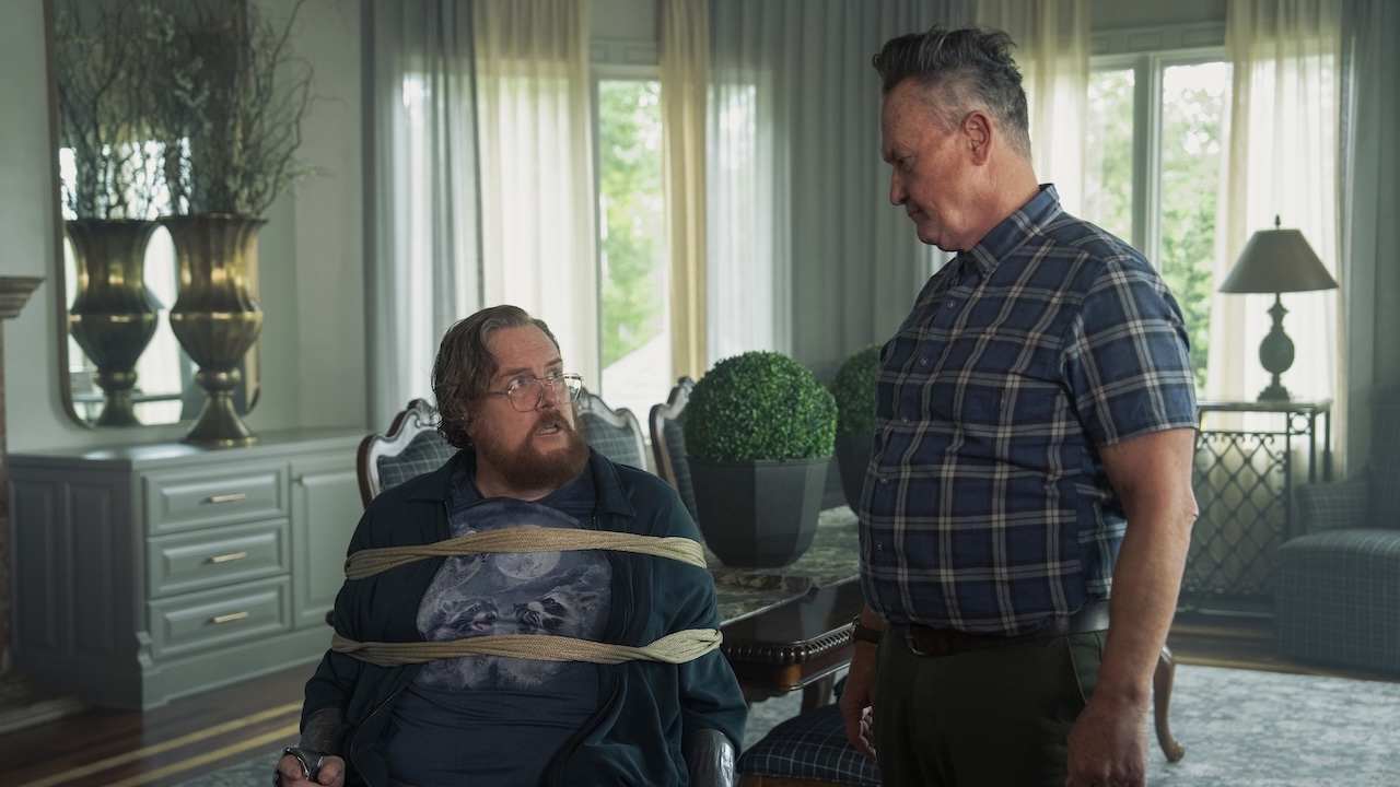 Earth-X Auggie Smith looking down at John Economos tied to a chair.