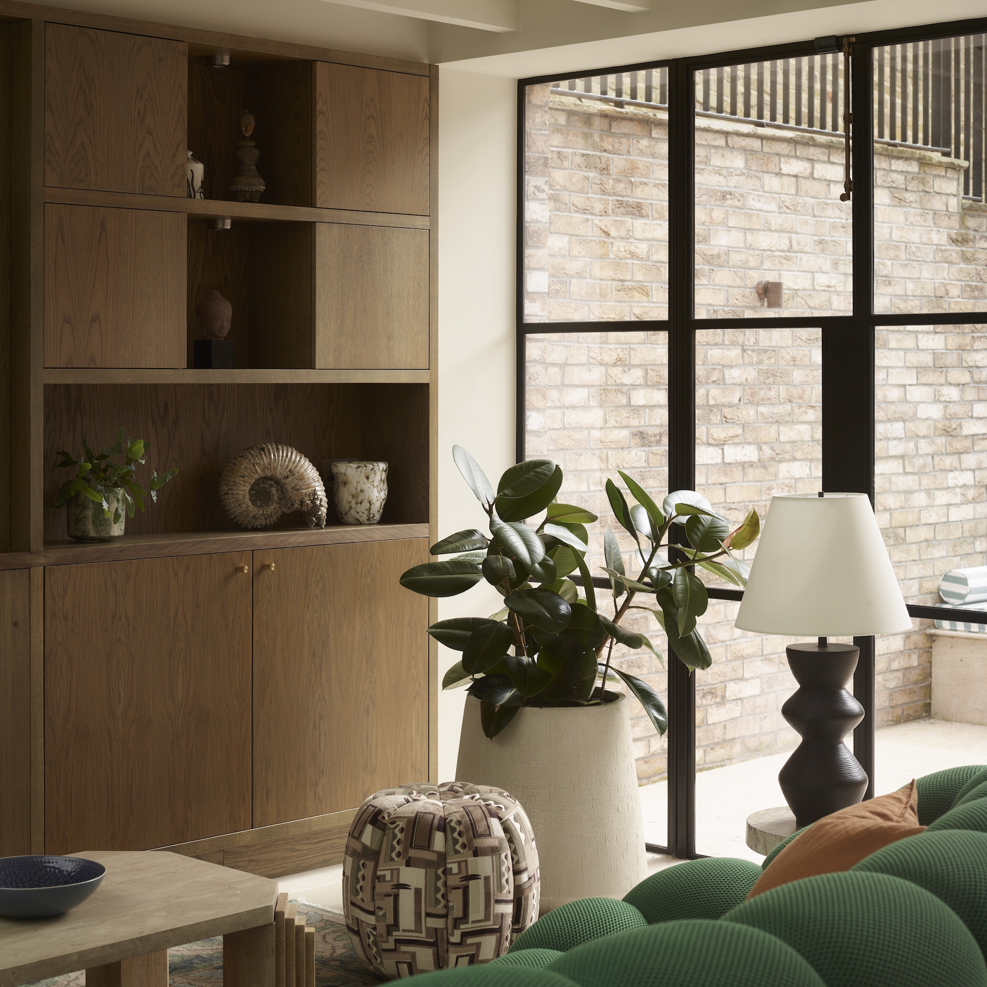 seating area in basement living space with green sofa and fitted wooden media cabinets