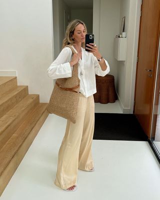 @anoukyve wearing a white blouse and tailored trousers