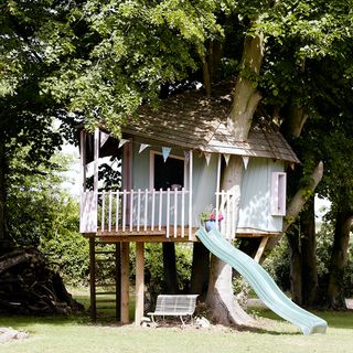 Pastel coloured wonky treehouse with a slide
