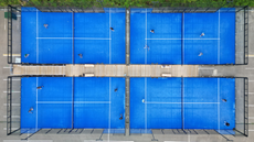 Four bright blue padel courts seen from above