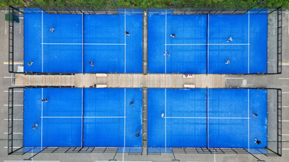Four bright blue padel courts seen from above