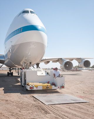 Aircraft tug driver Don Bailes tows SCA 911 onto steel plates after its final journey from NASA Armstrong's Palmdale facility to the nearby Joe Davies Heritage Airpark. The aircraft will be on permanent display at the historic outdoor museum from 10 a.m. to 4 p.m. Fridays through Sundays.