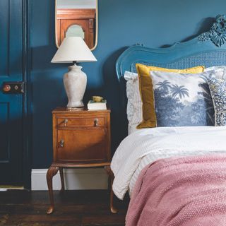 small bedroom with dark blue walls and a pink bedspread