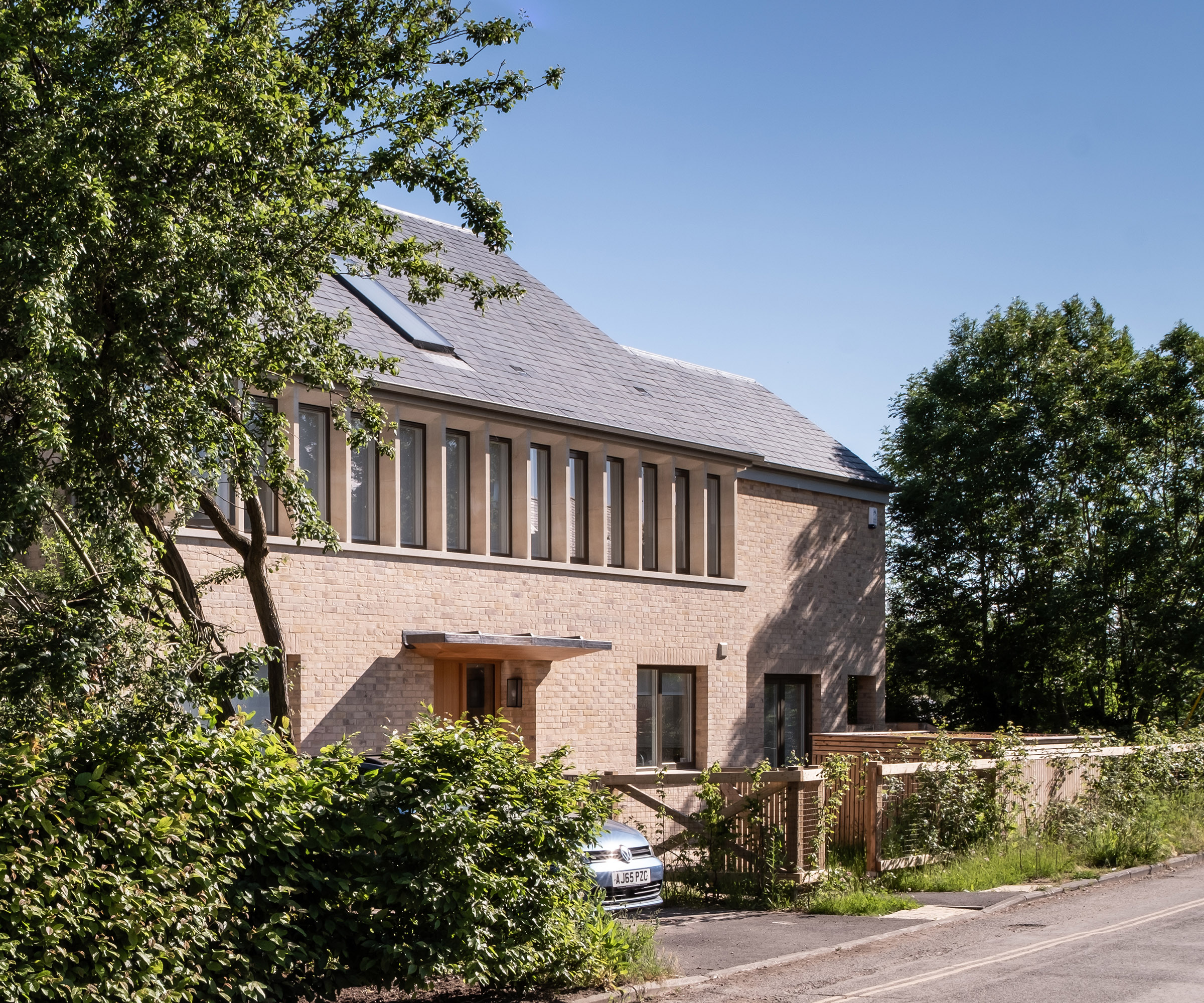 A self build with light stone with a row of windows on a sunny day