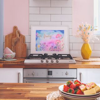 Kitchen with pink walls, wooden counter tops and a bowl of strawberries