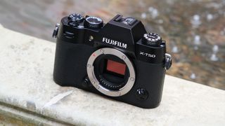 Fujifilm X-T50 camera on a stone wall in front of a pool of water