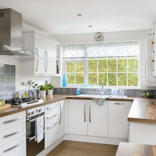 kitchen white walls wooden flooring and white windows microwave and white cabinet
