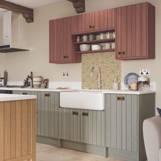 A kitchen with wood panelled cabinets painted in pastel pink, green and blue