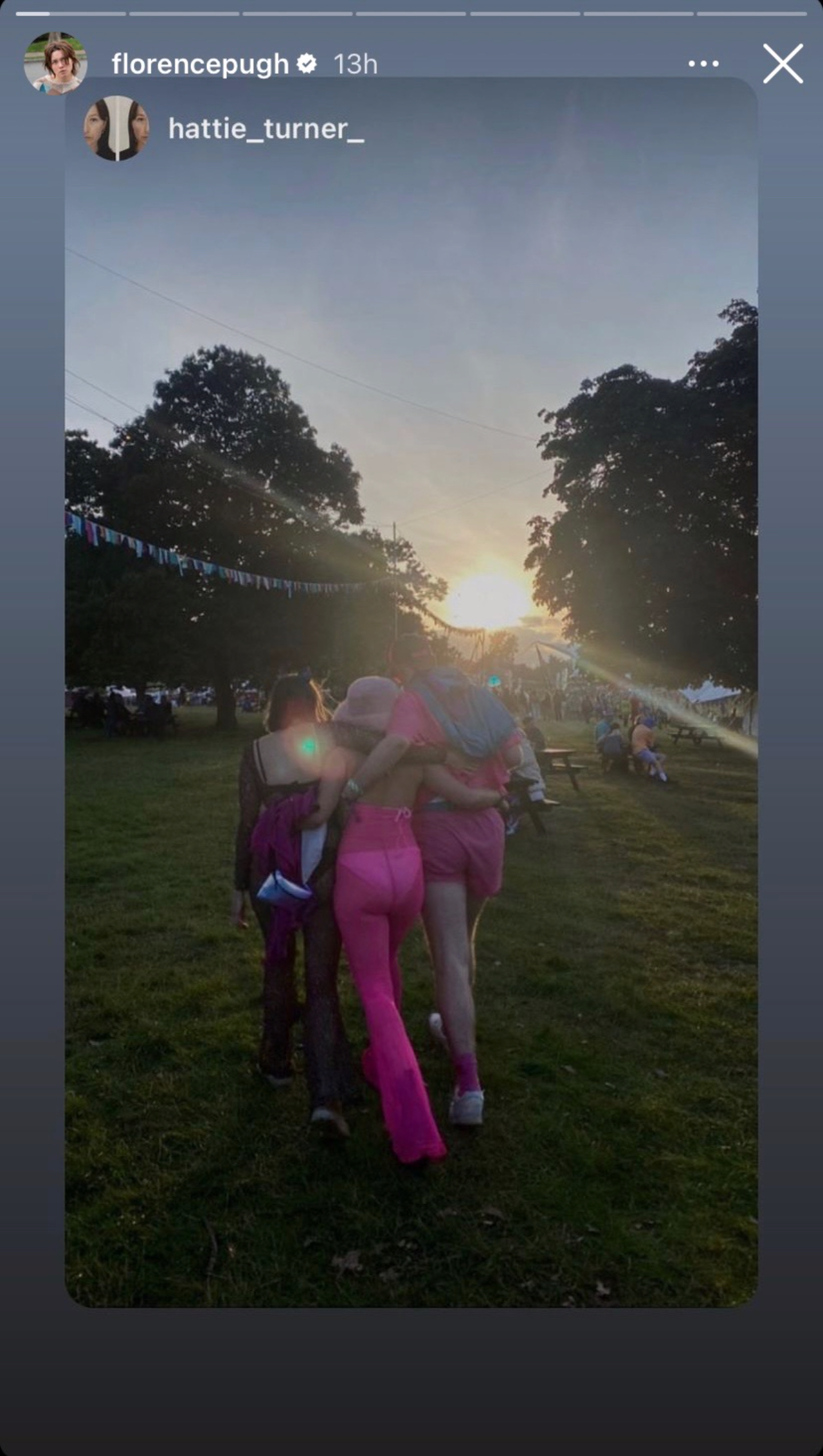Florence Pugh wearing Barbie pink at a Music festival photographed from behind with friends.