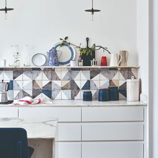 A white kitchen with graphic tiled splashback and a display shelf