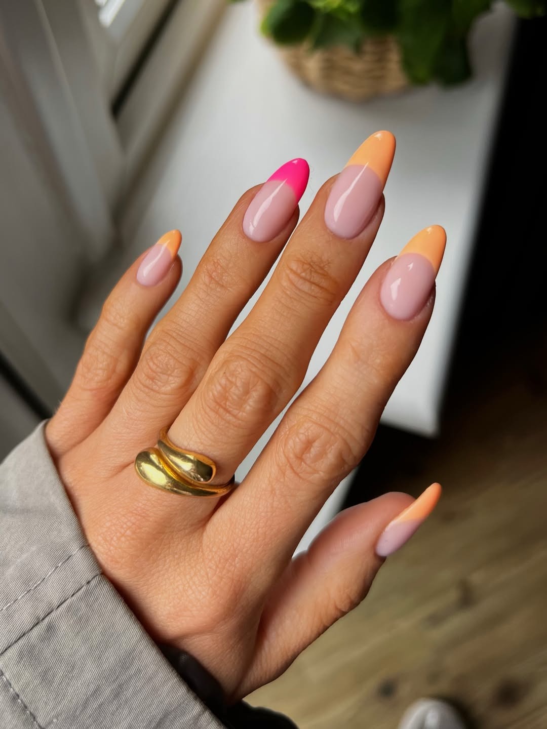 A French tip manicure featuring orange and pink French tip colours