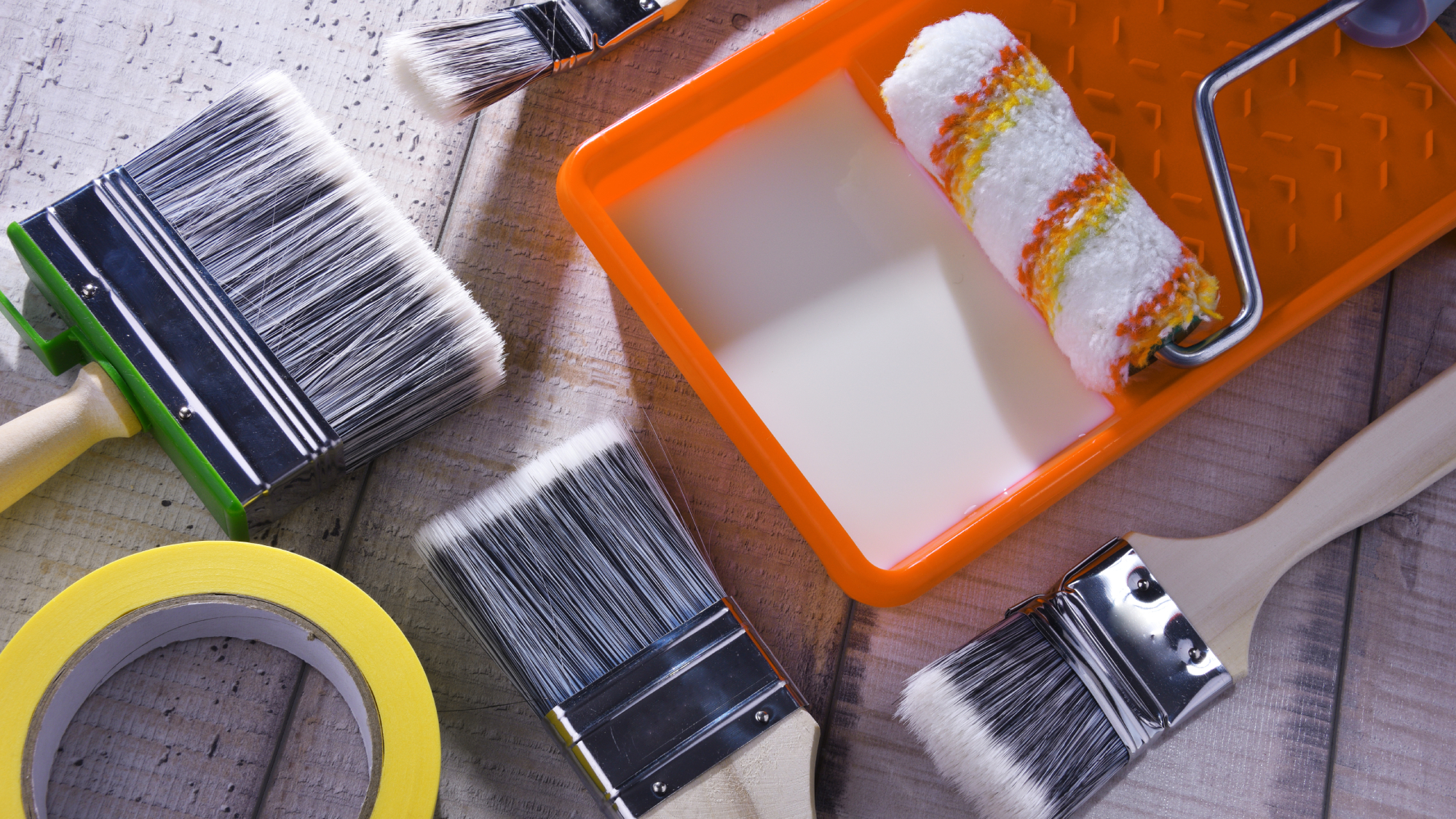 paint brushes, masking tape, paint roller and tray with paint