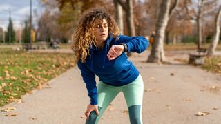Woman checking GPS watch during run in park