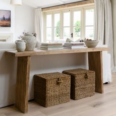 Console table in a neutral living room, with two large storage baskets sitting underneath it