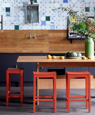 Blue and wooden kitchen with rustic blue tiles and red chairs