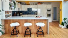 White gloss kitchen with wood island, fluffy bar stools and deep teal gloss metro tile splashback in a herringbone pattern