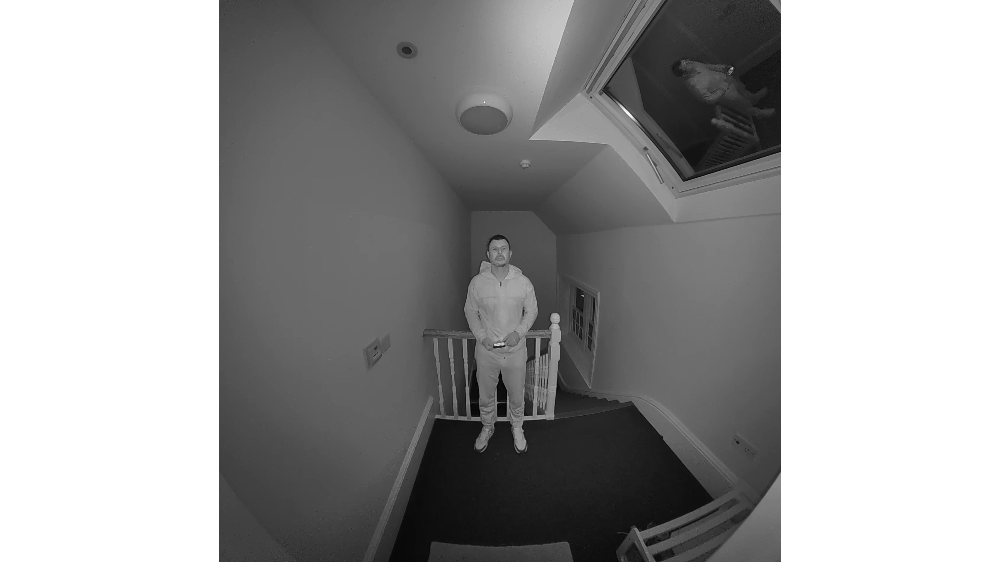 Black and white still of man standing outside door at night, captured by Ring Battery Video Doorbell Plus (2nd Gen)