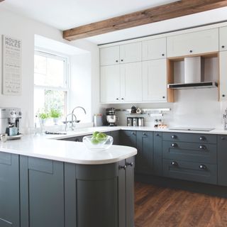 U-shaped kitchen with two-tone cupboards, white worktop and rounded peninsula