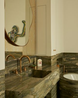 a bathroom with green marble counters and bath, and a brass tap