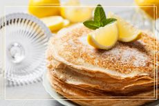 A stack of crepe style pancakes with lemon wedges on top