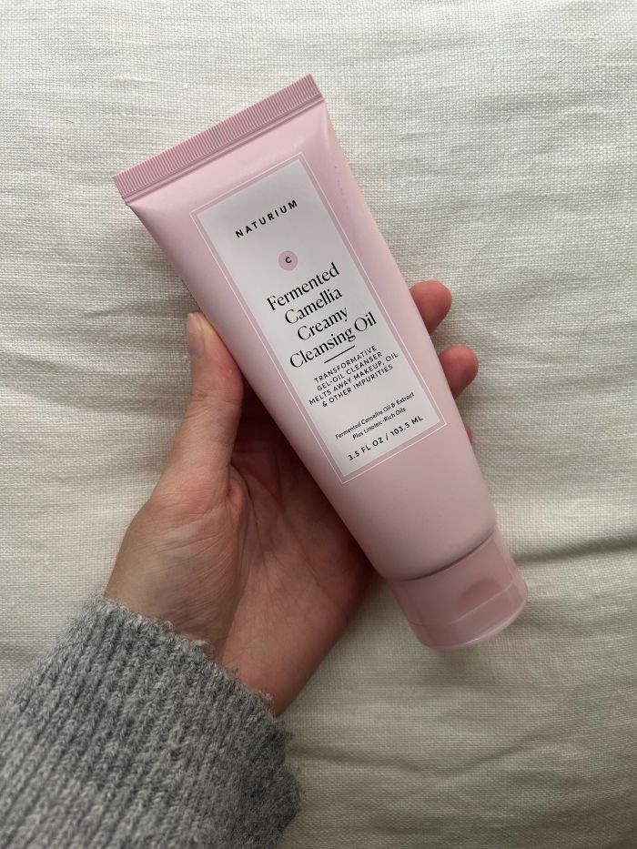 Junior beauty editor Grace Lindsay holding the Naturium Fermented Camellia Creamy Cleansing Oil