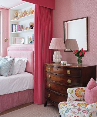 An alcove bed in a pink colored luxury bedroom idea with antique furniture.