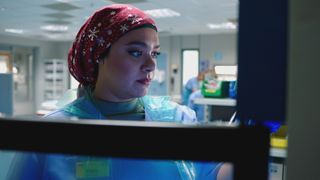 Nurse Rida Amaan wearing a red headscarf with a white snowflake design, looking into the rapidly emptying blood fridge.