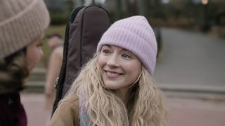 Beth smiling with a guitar in Dead City.