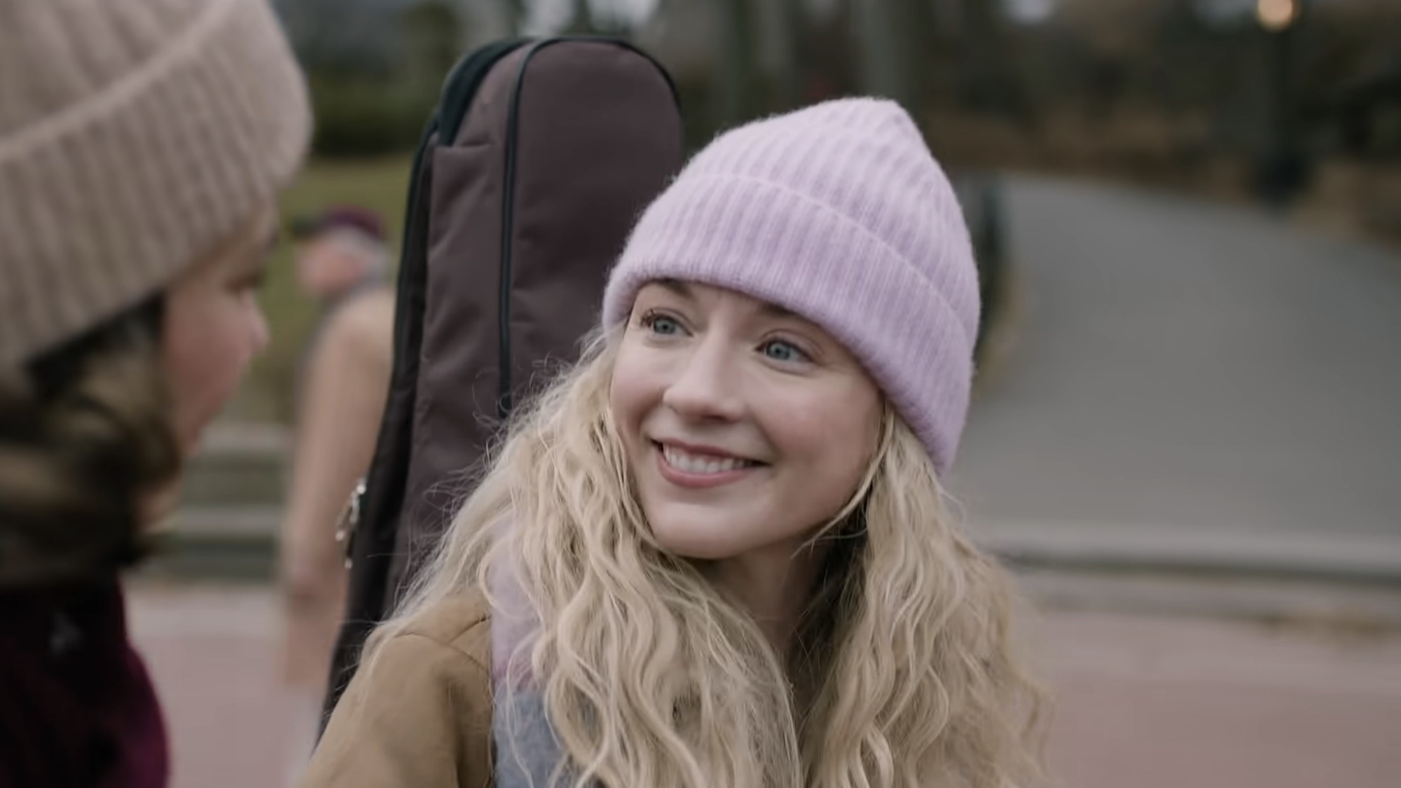 Beth smiling with a guitar in Dead City.