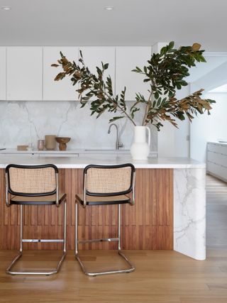 Modern kitchen with a wooden island that has a white marble waterfall countertop.