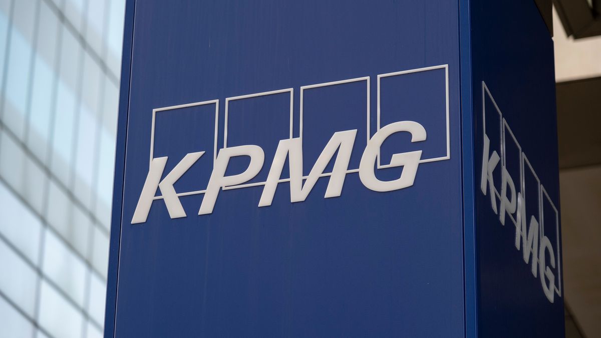 KMPG logo (the white letters &quot;KPMG&quot; against four white rectangles with blue centers) on a blue pillar outside the KPMG office.