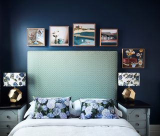 A bedroom with navy blue painted walls and a green headboard