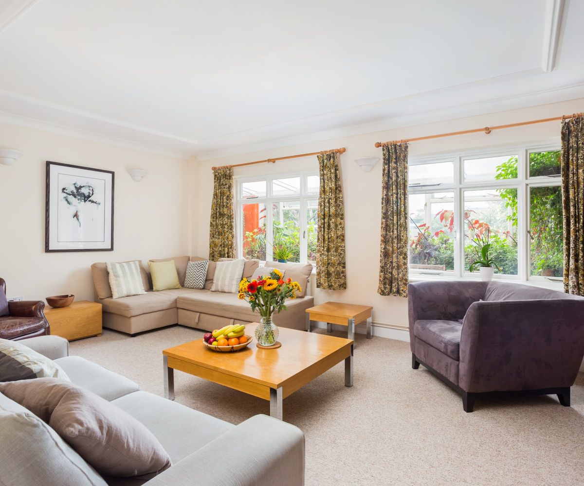 A living room with two windows with white carpet, walls and roof