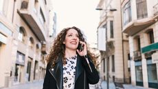 A woman talks on her phone as she walks through a street in Spain.