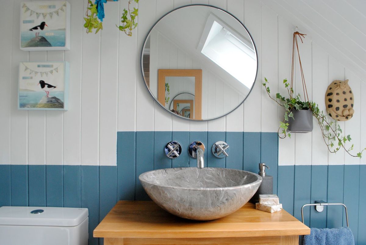 The bathroom has a grey stone bowl sink with a mirror above surrounded by white stone walls