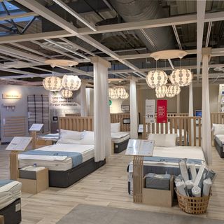 A mattress showroom with a wooden floor and multiple mattress on bed frames