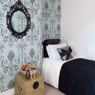 guest bedroom with wallpaper mirror and bed and cushions