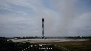 a black and white rocket rests on a landing pad beneath a cloudy sky