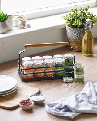 spice rack caddy on wooden countertop with spices, windowsill in the background