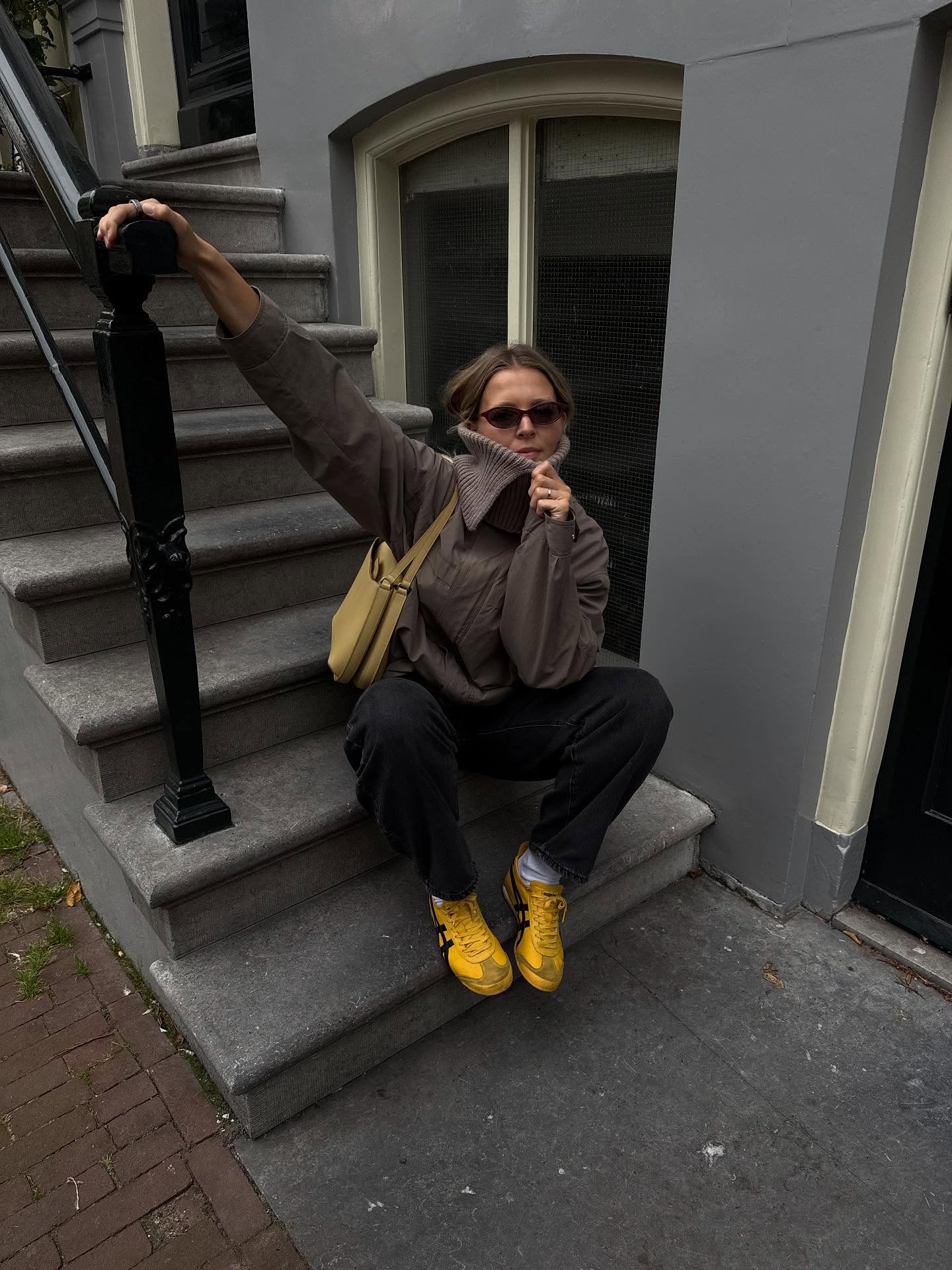 Hollie wears black pants, a brown coat, and yellow sneakers&amp;mdash;one of the biggest sneaker color trends of 2026.