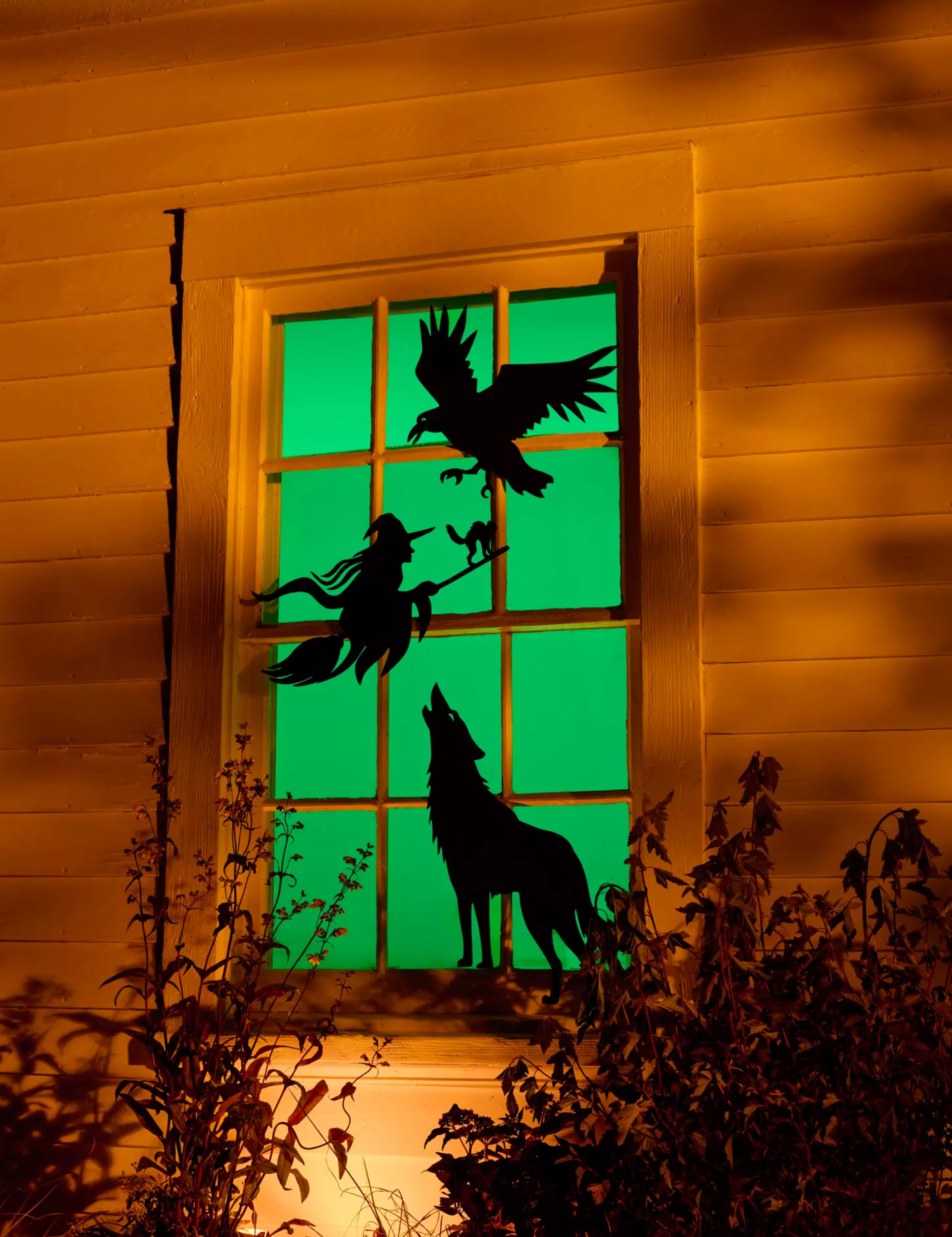 Spooky window decals hung along a green-tined exterior windowpane