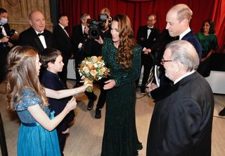 Catherine, Duchess of Cambridge is given a posy by 10 year old Poppy Clee and Rowan Clarke during the Royal Variety Performance at Royal Albert Hall